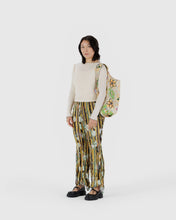 Load image into Gallery viewer, Person wearing a white top and patterned pants, holding a floral bag on a white background
